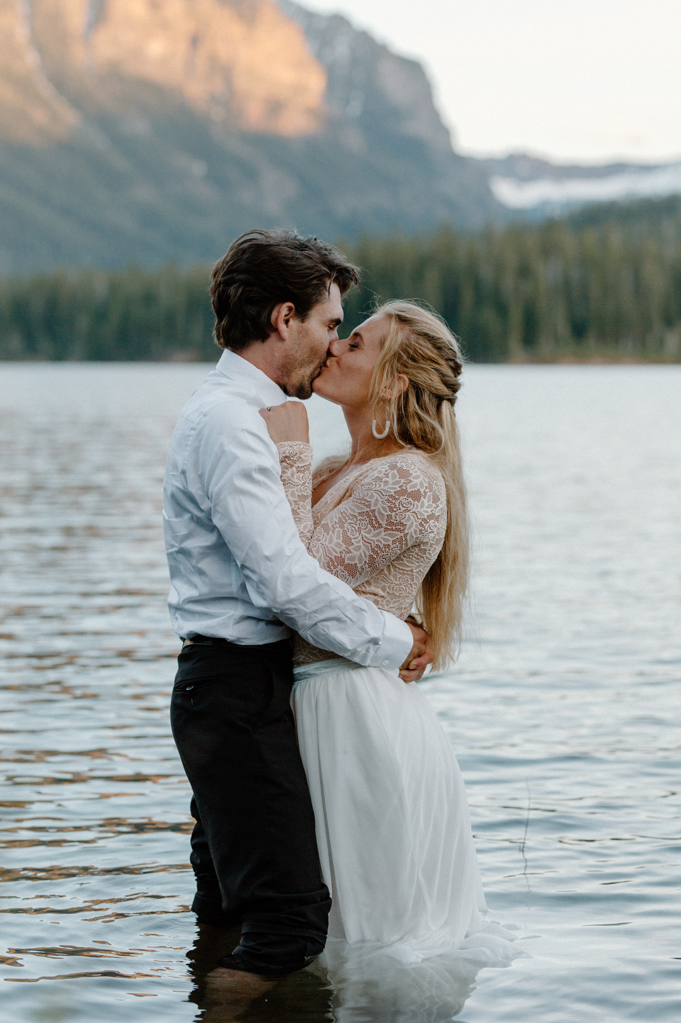eloping couple kisses in mountain lake