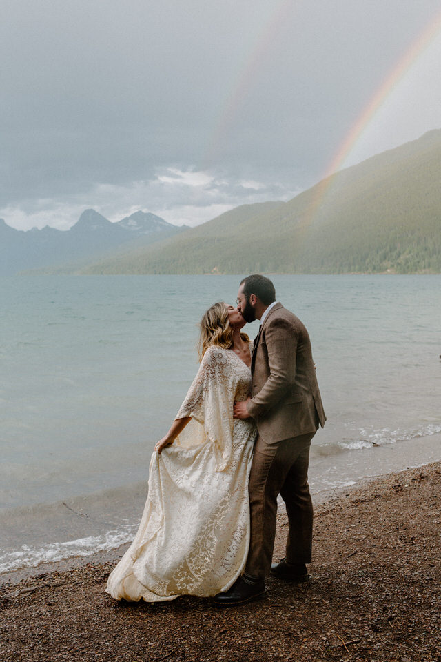 couple kisses under rainbow at lake mcdonald