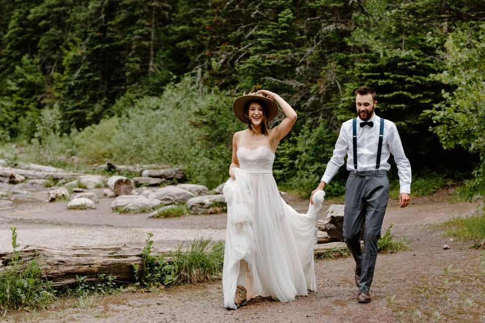 groom helps bride carry dress