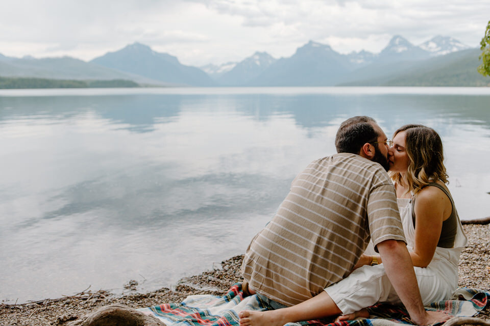 couple kisses against a blue lake mcdonald