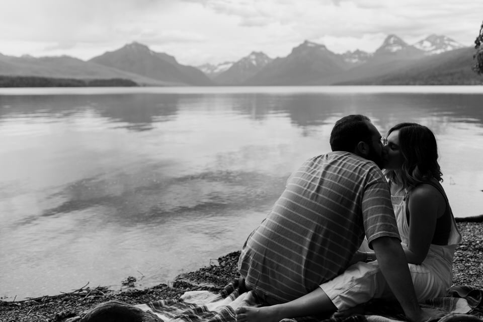 couple kisses against black and white mountains