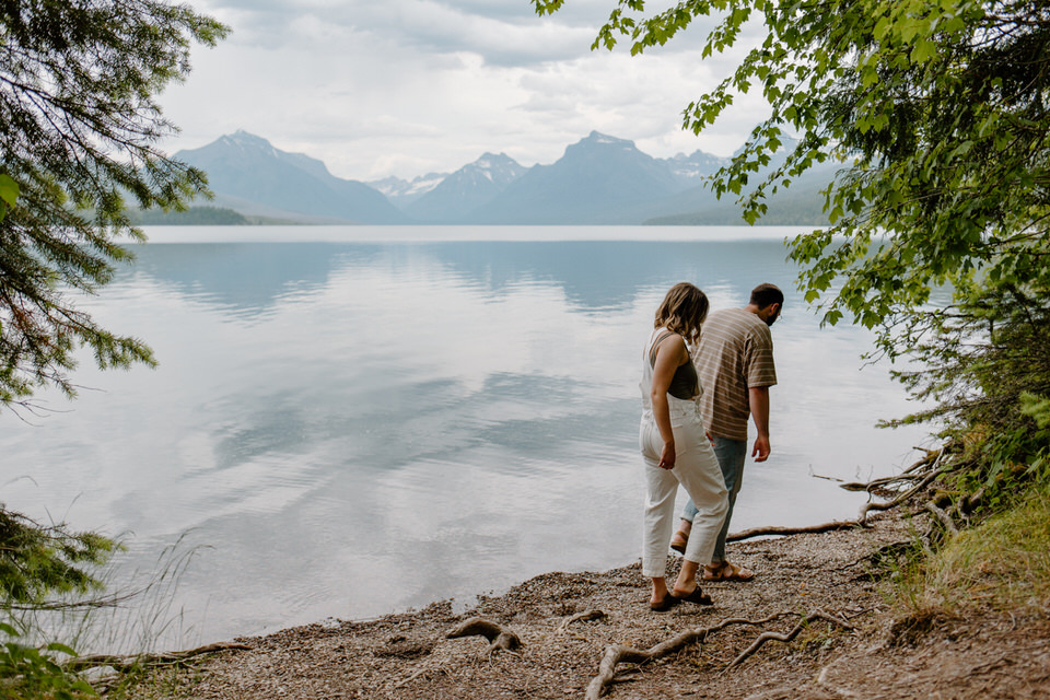 couple walks on shore of lake mcdonald