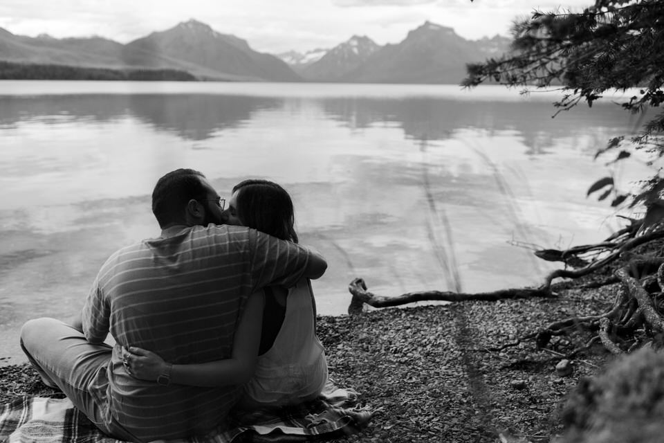 couple hugs and kisses at lake mcdonald
