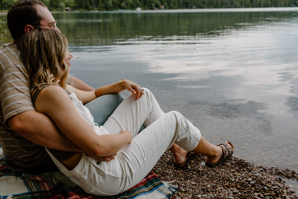 couple sits on the edge of lake mcdonald