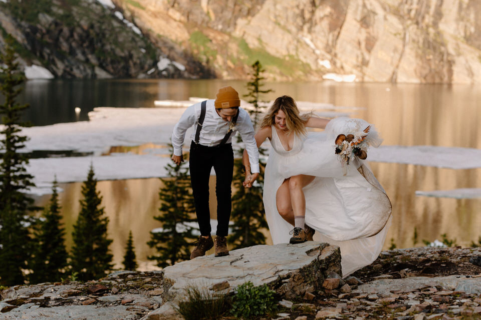 bride and groom hop across boulders in montana