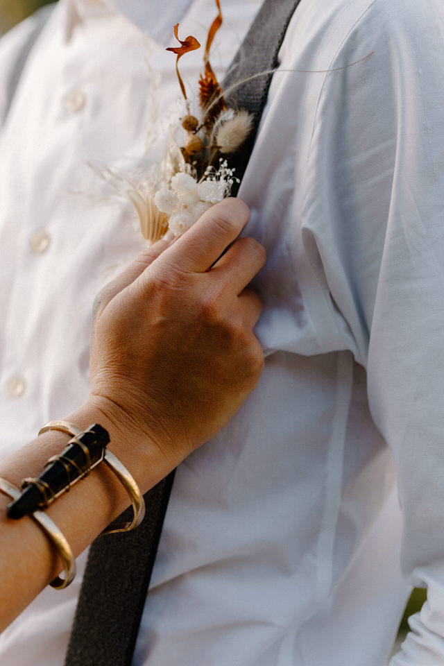 bride holds groom's indie boutonniere