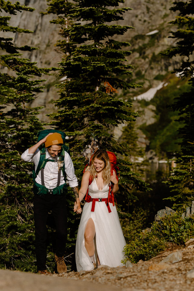 Bride and groom hike with backpacks on