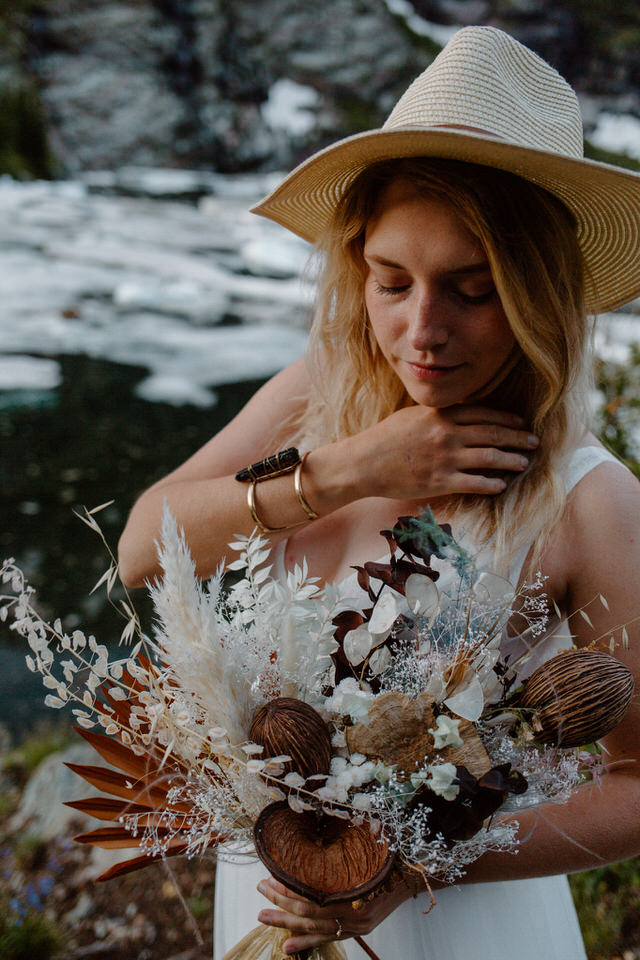 alternative bride looks at dried floral bouquet during elopement