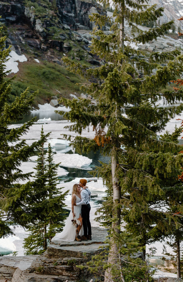eloping couple stands on boulder in front of icebergs